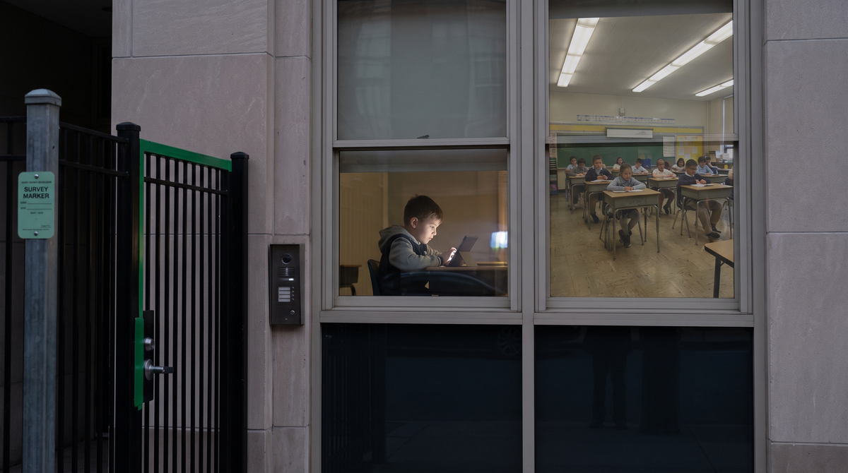 A child at a desk with a tablet viewed through a gated window, a public school classroom visible on the other side of the glass, survey-marker green on pale grey